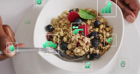 African american man checking ar nutrition icons over granola bowl with berries and mint