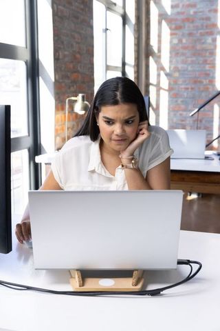 Focused woman working on laptop in contemporary office space