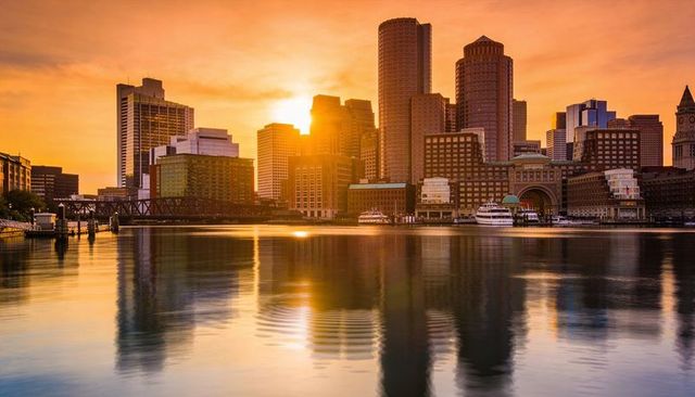 Golden sunset over harbor skyline reflecting on calm water with marina and bridge