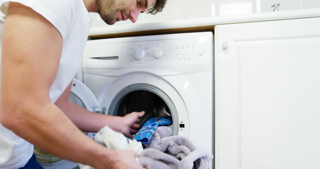 Man doing laundry at home. Ideal for content about household chores, home appliances, modern living, and daily routines. Image showcases domestic life and cleanliness.
