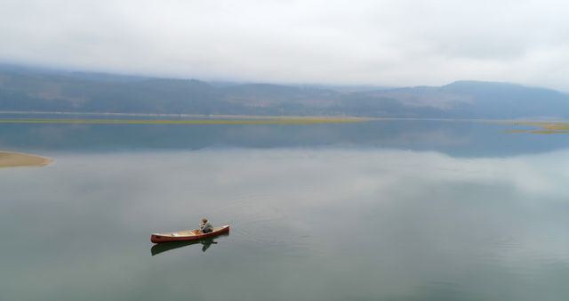 Solitary Canoe on Tranquil Lake with Foggy Mountains in Background - Download Free Stock Images Pikwizard.com