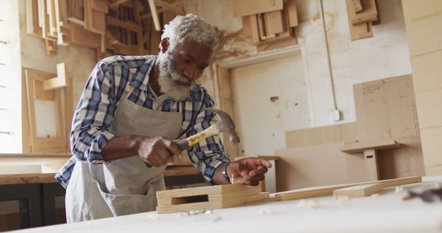 African american male carpenter hammering nails into the wood at a carpentry shop. Carpentry, craftsmanship and handwork concept