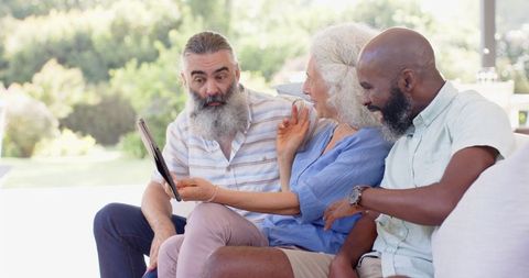 Senior Friends Enjoying Tablet Technology and Laughter Outdoors