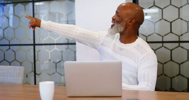 Smiling Elderly Man Pointing While Working in Modern Office - Download Free Stock Images Pikwizard.com