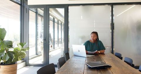 Woman in Meeting Room Reviewing Documents, Using Laptop