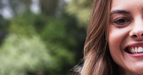 Half-Face Smiling Woman Outdoors with Lush Foliage Background