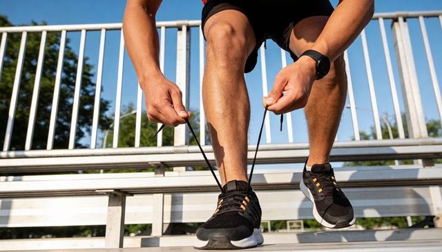 Runner tying shoelaces on stadium bleachers preparing for morning run and training session