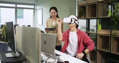 Asian coworkers engaged in virtual reality collaboration in modern office
