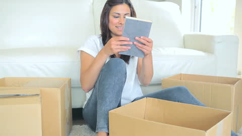 Joyful Woman Unpacking Books in New Home