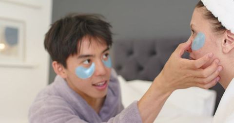 Couple applying hydrogel under-eye patches in bed during cozy at-home skincare routine