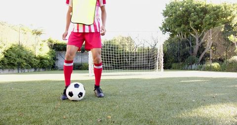 Teenage Boy in Yellow Pinnies Kicking Soccer Ball on Garden Pitch