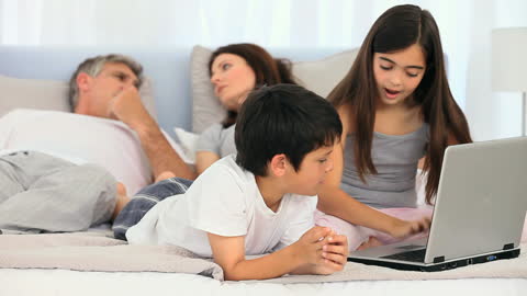 Children Engaged with Laptop While Parents Relax