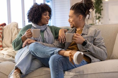 Couple sharing cozy coffee moment on light-colored sofa in relaxed living room