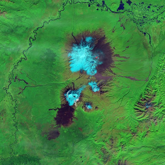 Satellite image shows active lava flow on Klyuchevskaya Volcano's western slopes in false-color. Taken by Landsat 8 on September 9, 2013, lava appears bright red, snow is cyan, and vegetation is green. Useful for studying volcanic activity, environmental science, and climate change impacts.