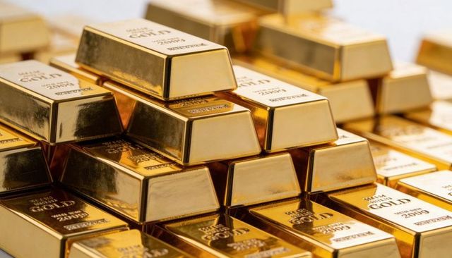 Stacked gold bullion bars glinting under warm light reflecting hallmarks and luxury