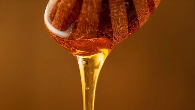 Dripping Honey from Wooden Dipper in Studio with Warm Tones