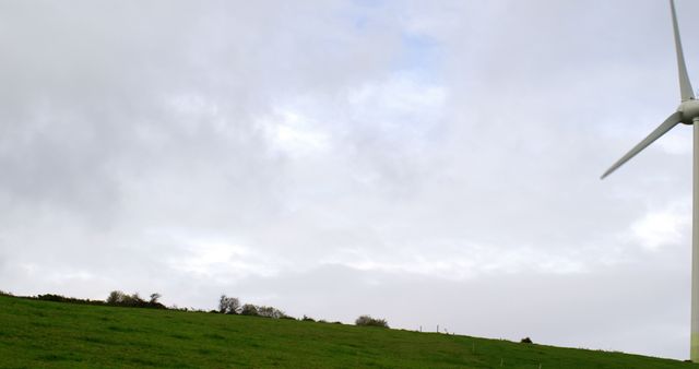 Wind turbine on cloudy day in grassy field - Download Free Stock Images Pikwizard.com