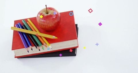 Stacking notebooks with apple and colored pencils on white back-to-school flatlay