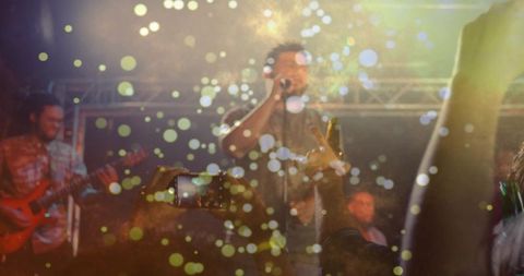 Energetic Live Concert Singer on Stage with Smartphone Recording and Golden Bokeh Lights