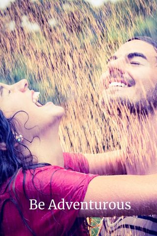 Laughing couple enjoying refreshing water droplets outdoors
