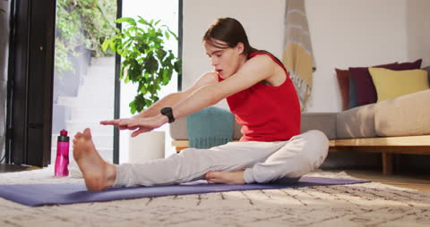 Caucasian Non-Binary Person Practicing Yoga at Home Stretching