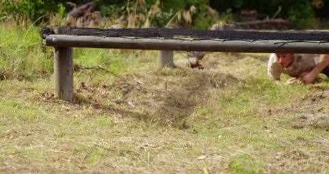 Caucasian Soldiers Crawling Under Obstacle Course Hurdles