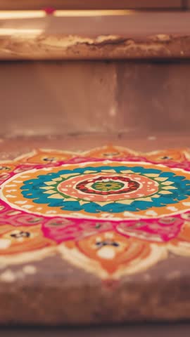 Vertical video revealing colorful rangoli on concrete porch step with geometric patterns