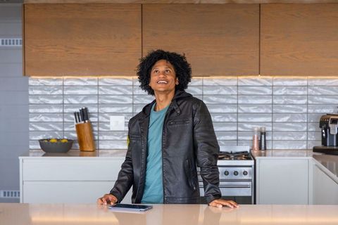African american man standing at modern kitchen wearing leather jacket using tablet looking up
