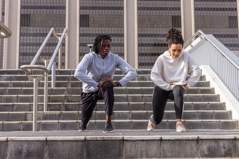 Urban fitness partners training on city steps lunging for outdoor workout motivation