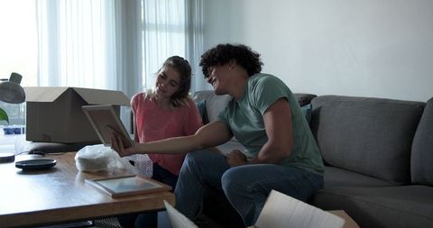 Young couple unboxing and admiring framed picture in cozy living room