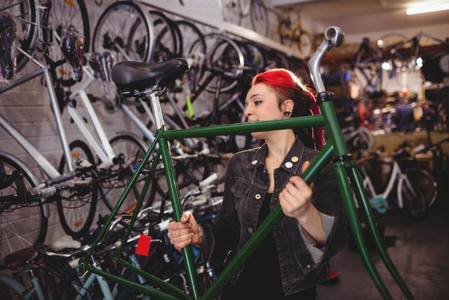 Mechanic repairing bicycle frame in a bike workshop, surrounded by various bicycles and tools. Ideal for use in content related to bicycle maintenance, repair services, cycling enthusiasts, and mechanic training.