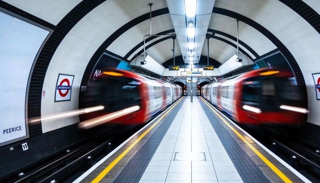 Blurring twin red trains passing central london underground platform with symmetric tunnel