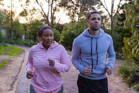 Diverse friends jogging in leafy park promoting fitness and well-being