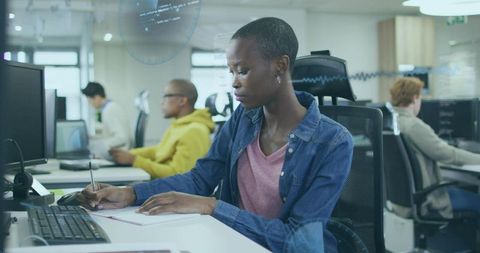 Focused professional writing notes in modern high-tech office