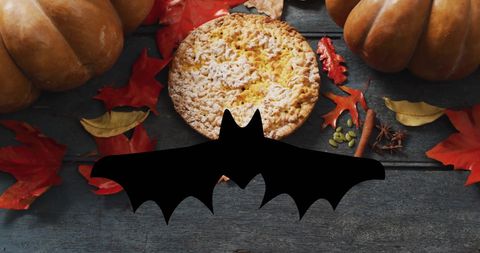 Halloween bat overlay with autumn leaves, pumpkins and pie