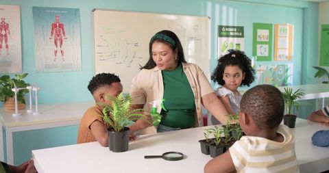 Teacher demonstrating plant care with elementary students in bright science classroom
