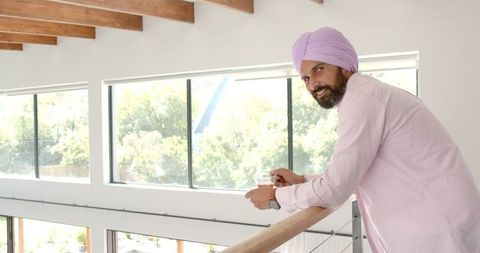 Smiling man in turban enjoying tea by bright window