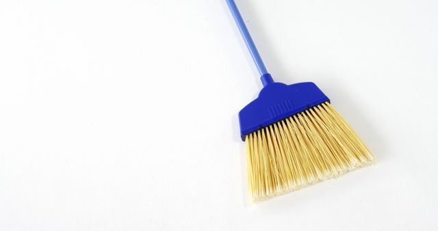 Blue plastic broom placed on a clean white surface. Ideal for articles, adverts, and blog posts related to housework, cleaning products, or sanitation. Can be used for highlighting cleanliness, promoting cleaning tools, and representing household chores.