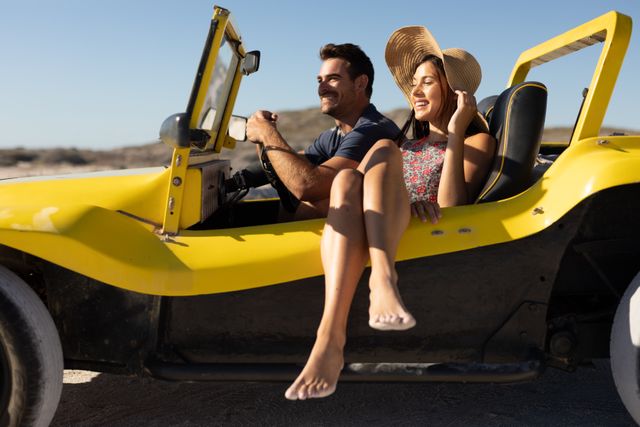 Happy caucasian couple sitting in beach buggy at sunny beach smiling and admiring the view. beach stop off on romantic summer holiday road trip.