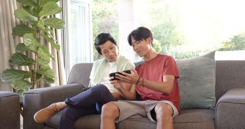 Father and Son Using Smartphone Together on Cozy Sofa