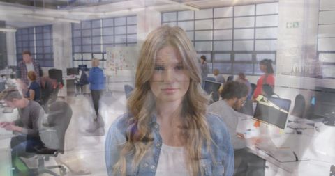 Young professional standing in modern open office with collaborative team working