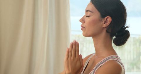 Serene Young Woman Meditating on Balcony Overlooking Scenic Landscape