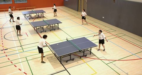 Energetic players engaged in recreational table tennis match in gym