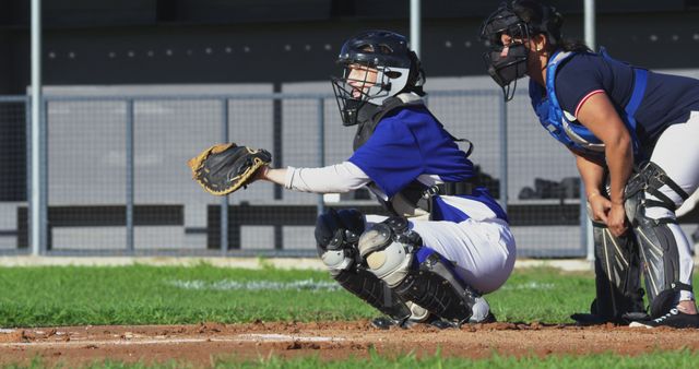 Catchers in full gear focused behind home plate during a baseball game. This image captures the intensity and skill required in baseball, ideal for use in sports marketing, training materials, blog posts about teamwork, articles on baseball strategy, and promotional material for sporting events.