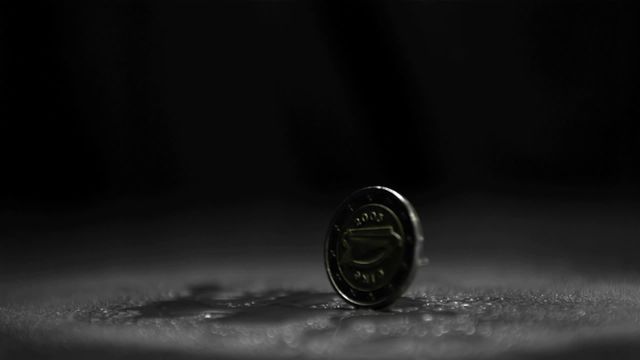 Two euro coin spinning against dark, black background in slow motion. Highlighted details including currency symbol and hardware finish. Ideal for use in presentations or media related to finance, investment, European currency, economic studies, and promotional content conveying wealth, stability, and financial movement.