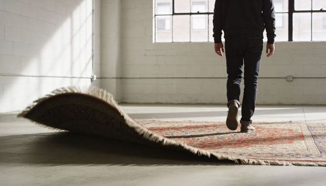 Man walking across vintage rug in sunlit industrial loft with concrete floor