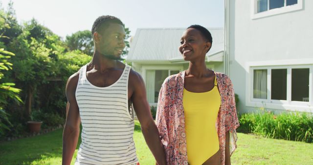 Happy african american couple walking holding hands in sunny garden smiling - Download Free Stock Photos Pikwizard.com