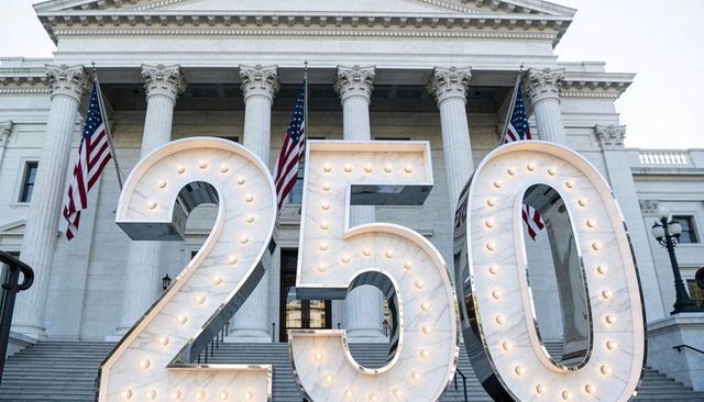 Giant marquee numerals 250 lighting up government building steps with american flags