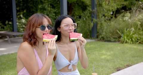 Two friends enjoying watermelon by poolside