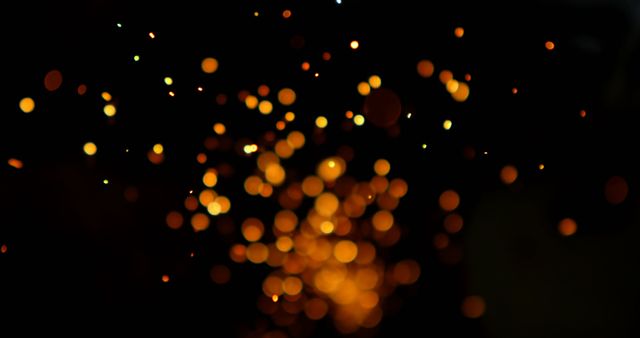 Abstract golden bokeh light spots floating in dark. Perfect for festive, celebration, or party themes. Can be used in holiday graphics, website backgrounds, greeting cards, or advertisements to evoke a sense of magic and excitement.